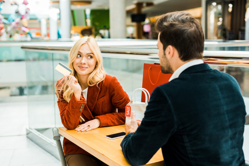 customer relationships smiling couple with credit card sitting in cafe in shopping mall